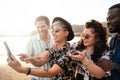 Group of multiracial happy young friends laughing, taking selfie with mobile phone, having fun together on the beach. Multi ethnic Royalty Free Stock Photo