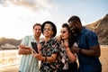 Group of multiracial happy young friends laughing, watching something funny in social media on mobile phone, having fun together Royalty Free Stock Photo