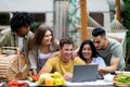 Group of multiracial millennial friends using laptop on autumn camping trip to countryside, chatting online, having fun