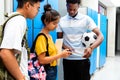 Group of multiracial teen students with smart phone in high school corridor