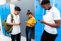 Group of multiracial teen students using their mobile phones in high school corridor