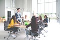 Group of multiracial young creative team talking, laughing and brainstorming in meeting at modern office concept. Man standing and Royalty Free Stock Photo