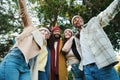 A group of multiracial young friends having fun together in a park doing autumn weekend activities wearing coats and Royalty Free Stock Photo