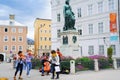 Group of musicians perform in street of city town square under statue of Mozart