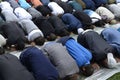 Group of muslim men kneeling and praying on lawn