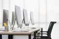 Group of new clean computers on desk in modern office with windows in background Royalty Free Stock Photo