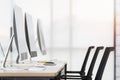 Group of new clean computers on desk in modern office with windows in background Royalty Free Stock Photo