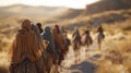 A group of nomadic people faces hidden by headscarves walk in unison with camels across the vast sp desert landscape. . Royalty Free Stock Photo