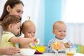 Group of nursery babies eating healthy food with babysitter help. Lunch break in creche. Time to eat in daycare Royalty Free Stock Photo