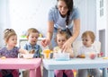 Group of nursery babies eating healthy food lunch break together with kindergartener