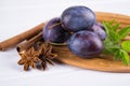 Group off purple plums on a white kitchen board with fresh mint, cinnamon, anise