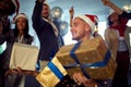 Group of office workers celebrating Christmas.Young smiling man in santa hat at Xmas party