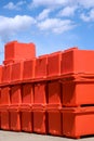 Group of orange foldable ice buckets stack on courtyard outside of storage against blue sky Royalty Free Stock Photo