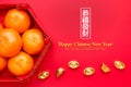 Group of orange tangerine in Chinese pattern tray with gold ingots on red table.Chinese Language on ingot mean wealthy and