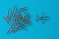 Group of ordinary paper clips with airplane shaped one on blue background.