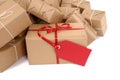 Untidy heap of brown paper packages, one unique with red gift tag, isolated Royalty Free Stock Photo