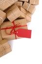 Border of small pile of brown paper parcels, red gift tag, isolated Royalty Free Stock Photo