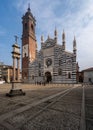 Group of people ambling past the towering Monza Cathedral on a sunny day. Italy.