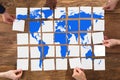 Group Of People Arranging The World Map Puzzle Royalty Free Stock Photo