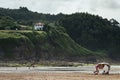 Group of people at the beach with a traditional house on the green cliff in Asturias, Spain Royalty Free Stock Photo