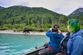 Group of people on a boat taking pictures of bear in green mountains