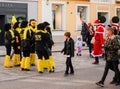 A group of people in carnival costumes talk in front of a building