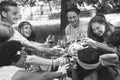 Group of people cheering with red glasses of wine - Happy young friends enjoying picnic bbq in a park with food and drink Royalty Free Stock Photo