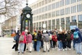 group of people, children walking with guide through streets of city Hannover, green pedestal with KrÃÂ¶pke clock, concept of