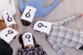 A group of people with closed faces with a question mark on the floor on the left