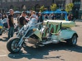 Group of people curiously looking at and experiencing spectacular three wheeler motorbike