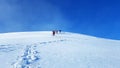 Group of people descends from the snow-covered peak of the mountain. Winter mountain tourist hiking tours