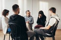 Group of people of different ages sits in a circle during a meeting with a professional therapist