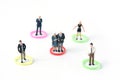 A group of people of different ages stand in different color circles. Miniature people figure