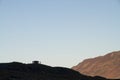 Group of people, distant unidentifiable in silhouette on hill, morning lit mountainside behind