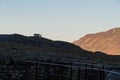 Group of people, distant unidentifiable in silhouette on hill, morning lit mountainside behind