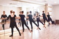 Group of people doing exercises using barre in gym with focus to fit athletic toned .woman in foreground in health and fitness Royalty Free Stock Photo