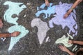 A group of people drawing with colored chalks on the floor with his hands in the street a map of the world Royalty Free Stock Photo