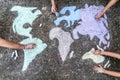 A group of people drawing with colored chalks on the floor with his hands in the street a map of the world Royalty Free Stock Photo