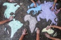 A group of people drawing with colored chalks on the floor with his hands in the street a map of the world Royalty Free Stock Photo