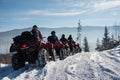 Group of people driving four-wheelers ATV bikes on snow in winter Royalty Free Stock Photo