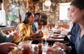 Group Of People Eating In Restaurant Of Busy Traditional English Pub