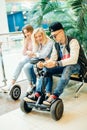 Group of people on electric scooter hoverboard sitting at bench and using phone Royalty Free Stock Photo