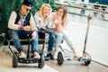 Group of people on electric scooter hoverboard sitting at bench and using phone Royalty Free Stock Photo