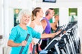 Group of people on elliptical trainer exercising in gym