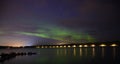 Group of people enjoying aurora borealis northern light unther the cloudy starry dark blue sky and water reflection Royalty Free Stock Photo