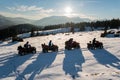 Group of people enjoying sunset on quad bikes on snow in the the mountains in winter Royalty Free Stock Photo