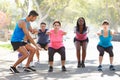 Group Of People Exercising InStreet With Personal Trainer