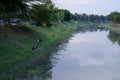 A group of people fishing by the river on the outskirts of the city