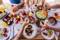 Group of people friends or family caucasian celebrate together and enjoy a table full of fresh and coloured healthy food - concept