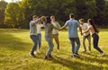 Group of a students friends playing outside in the park standing in a circle and holding hands. Royalty Free Stock Photo